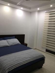 a bedroom with a bed and a window with blinds at Comfortable Apto en Hacienda Peñalisa in Ricaurte