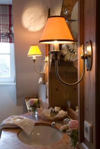 a bathroom with a sink with a lamp and a mirror at Brauereigasthof-Hotel Aying in Aying