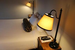 a bed with a lamp and a book on a table at Timbers Inn in Eugene