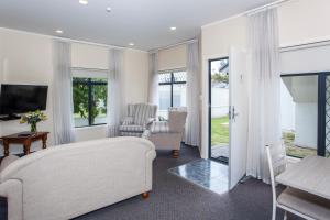 a living room with a couch and chairs and a television at Te Mata Lodge in Havelock North