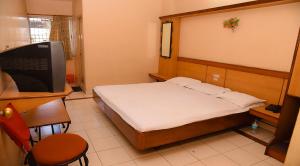 sypialnia z łóżkiem, biurkiem i telewizorem w obiekcie Hotel Vishnu Residency w mieście Visakhapatnam