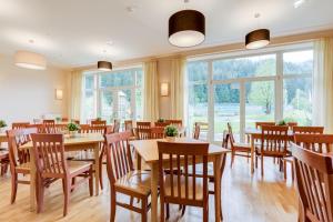 ein Restaurant mit Holztischen, Stühlen und Fenstern in der Unterkunft JUFA Hotel Veitsch in Veitsch