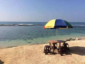 a table and chairs under an umbrella on the beach at Sunset Surfing Beach Resort in Matara