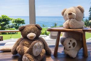 two teddy bears sitting on a table with the ocean in the background at Hai Yue Homestay in Yanliau