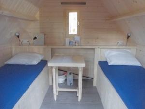 a room with two beds and a table in a cabin at Vakantiepark 't Urkerbos - Kabouterhuisje in Urk