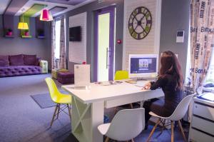 a woman sitting at a desk with a computer in a room at Good Night Hotel in Odesa
