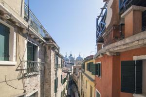 an alley between buildings with domes in the distance at Hotel Orion in Venice