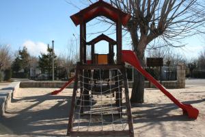 un parque infantil con un tobogán rojo en un parque en Camping Pico De La Miel, en La Cabrera