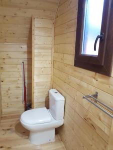a bathroom with a white toilet in a wooden wall at Camping Pico De La Miel in La Cabrera