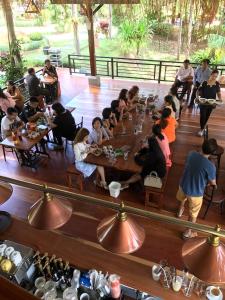 un grupo de personas sentadas en mesas en un restaurante en Chuanthanapanya Resort en Amphoe Sawang Daen Din