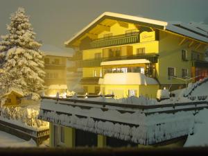 ein großes gelbes Gebäude mit Schnee darauf und einem Weihnachtsbaum in der Unterkunft Landhaus Krenn in Bad Kleinkirchheim