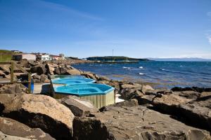 un grupo de mesas azules sobre rocas cerca del agua en Malarhorn Guesthouse, en Drangsnes