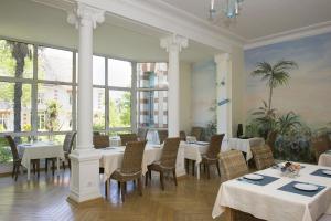 a restaurant with white tables and chairs and large windows at Résidence de Tourisme Vacances Bleues Villa Regina in Arcachon
