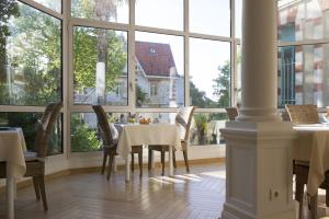a dining room with a table and chairs and windows at Résidence de Tourisme Vacances Bleues Villa Regina in Arcachon