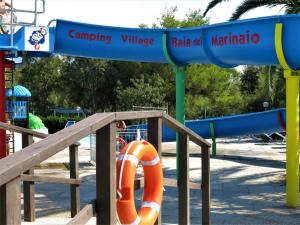 a slide at a playground with an orange life jacket at Camping Village Baia del Marinaio in Vada