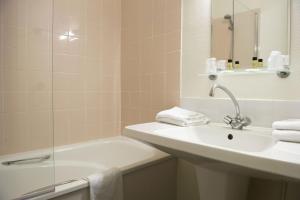 a bathroom with a sink and a tub and a mirror at Résidence de Tourisme Vacances Bleues Villa Regina in Arcachon