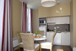 a kitchen with a table and chairs in a room at Résidence de Tourisme Vacances Bleues Villa Regina in Arcachon