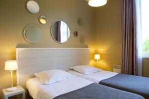 a bedroom with two beds and mirrors on the wall at Résidence de Tourisme Vacances Bleues Villa Regina in Arcachon