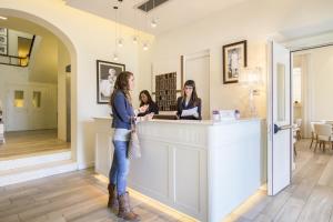 zwei Frauen stehen an einem Tresen in einem Salon in der Unterkunft Hotel Italia in Siena