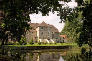 uma casa velha com um reflexo na água em Hotel Wasserschloss Mellenthin em Mellenthin