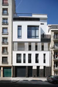 a white building with windows and a car parked in front at Veeve - Saint-Lambert Deluxe in Paris
