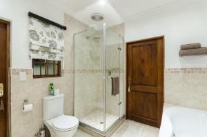 een badkamer met een toilet en een glazen douche bij Nut Grove Manor Boutique Hotel in White River