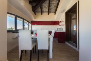 a kitchen with white chairs and red cabinets at AnaeleHouseapartments LTB in Arborea