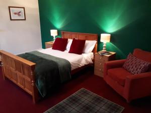 een groene slaapkamer met een bed en een rode stoel bij Rigg House B&B in Kirkconnel