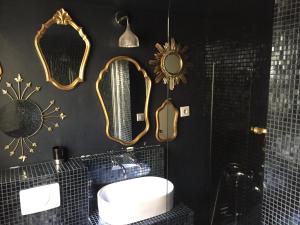 La salle de bains est pourvue de murs noirs, de miroirs et d'un lavabo. dans l'établissement Mon Refuge Urbain, à Montpellier