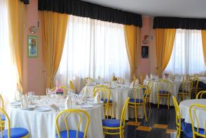 een feestzaal met tafels, stoelen en gordijnen bij Villaggio & Residence Club Aquilia in Badolato