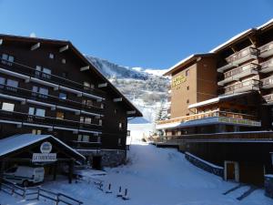 a hotel in the snow next to a building at R&eacute;sidence Alpinea in M&eacute;ribel