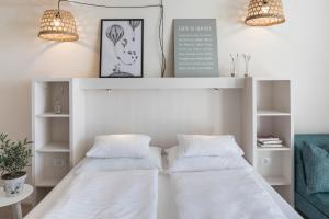 two beds in a bedroom with two lamps and a couch at Falkensteiner Hotel Park Punat in Punat