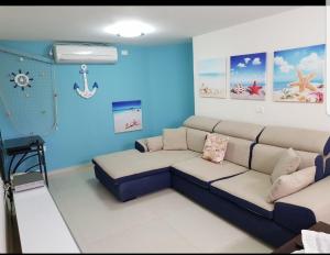 een woonkamer met een bank en een blauwe muur bij mi casa es su casa in Ashkelon