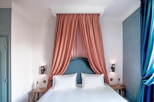a bedroom with a white bed and white curtains at Hotel des Grands Boulevards in Paris