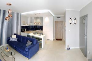 a living room with a blue couch and a kitchen at Apartamenty Klifowa in Rewal +12 photos