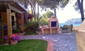 patio trasero con patio de piedra y chimenea en Residence Cala Silente, en Capoliveri