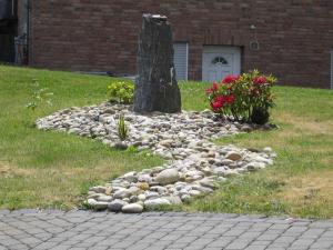 a rock garden in the grass with a tree and flowers at Ferienwohnung Haus Andre _ fuer 4 in Ulmen
