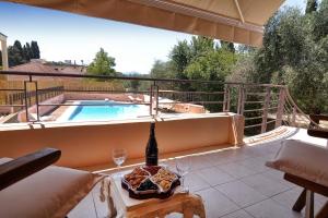 patio con piscina e tavolo con bottiglia di vino di Villa Figareto a Città di Corfù