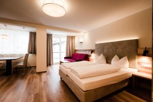 una habitación de hotel con una cama grande y una mesa en Aparthotel Dorfplatzl Garni, en Tux