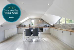 eine Küche mit weißen Schränken und einem Tisch und Stühlen in der Unterkunft Swansea Valley Holiday Cottages in Cilybebyll