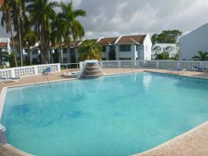 a large blue swimming pool in front of a house at Point Village Studio in Negril
