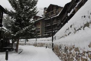 a building covered in snow next to a tree at Ski Andorra Tarter Chalet Lodge in El Tarter
