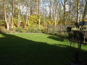 ザルシュテットにあるMessezimmer Hartwichの塀と木が植えられた広い緑の庭