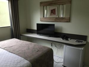 a bedroom with a bed and a desk with a television at Hotel Porto Bello in Cáceres
