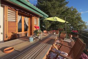 una terraza de madera con sillas y sombrilla en Magma Guest House, en Ragalna