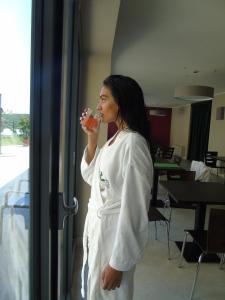 a woman in a white robe drinking from a glass at SPA Roero Relax Resort in Canale