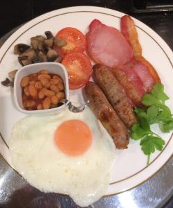 a plate of breakfast food with eggs sausage beans and tomatoes at Vine Cottage in Farnham