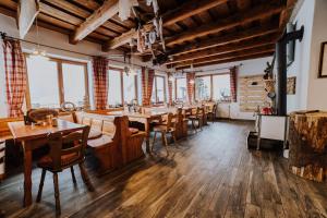 a restaurant with wooden tables and chairs and windows at Berggasthof Hochpröller in Sankt Englmar