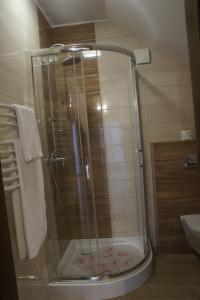 una ducha con puerta de cristal en un baño en Pensjonat Perła Pienin, en Grywałd