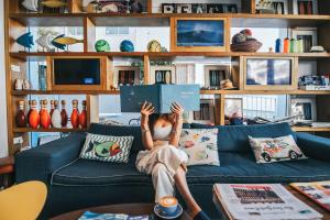 
a woman sitting on a couch in a living room at Yam Hotel - an Atlas Boutique Hotel in Tel Aviv
